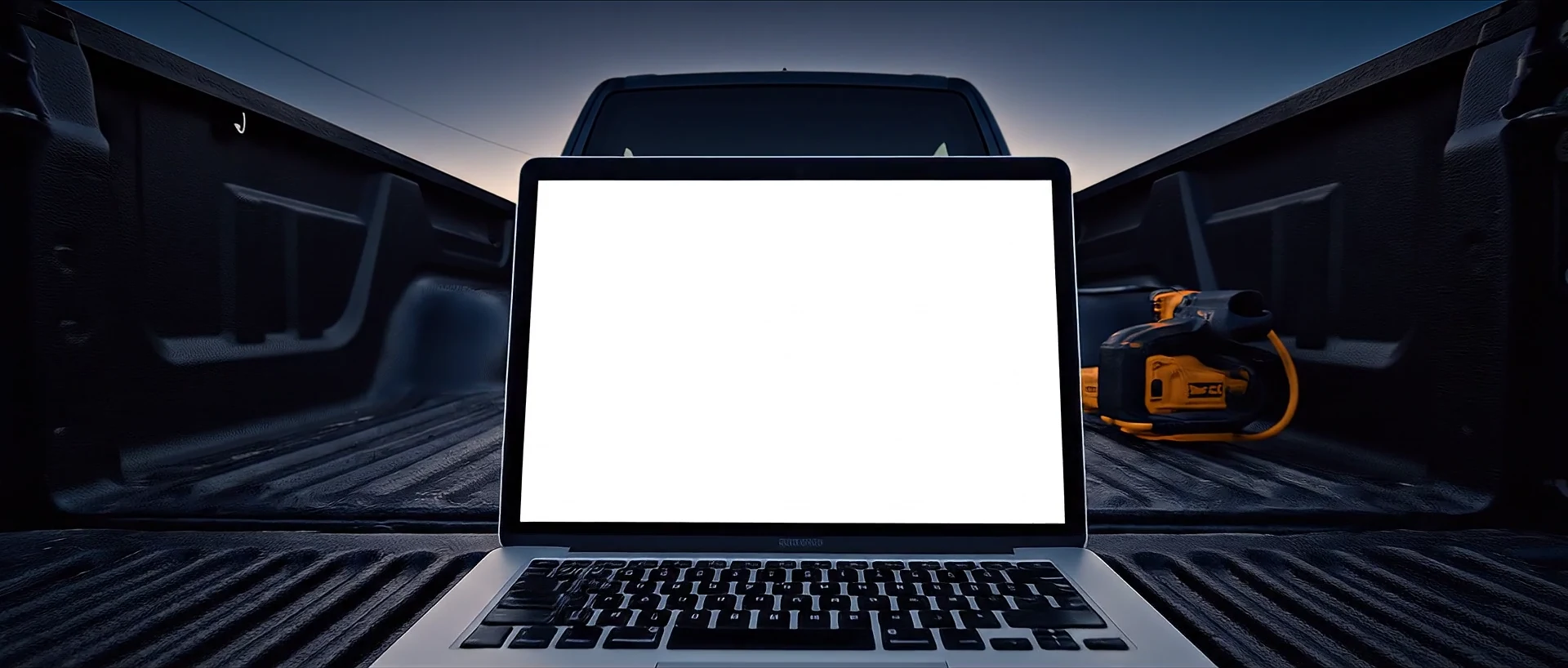 A laptop running BuilderOS on the tailgate of a ute at a residential build site at dusk.